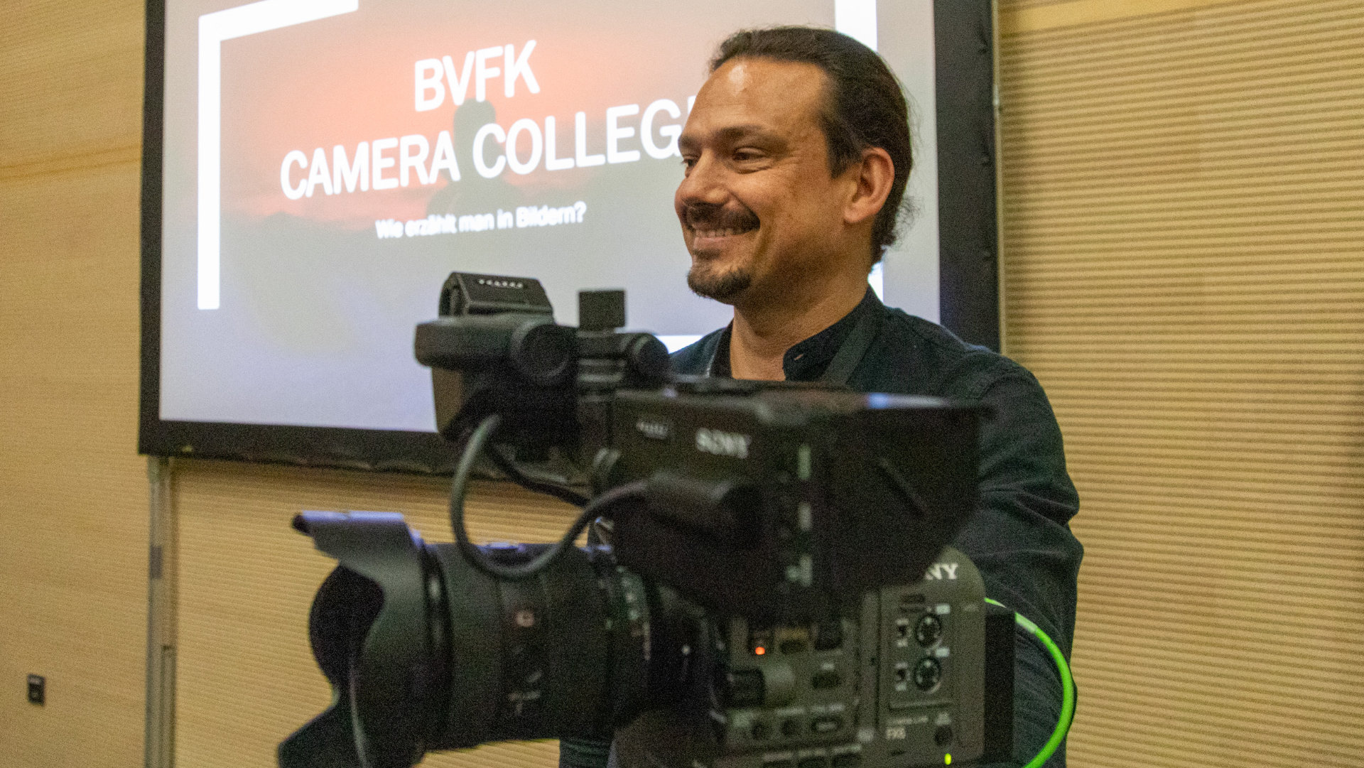 Man stands behind a film camera