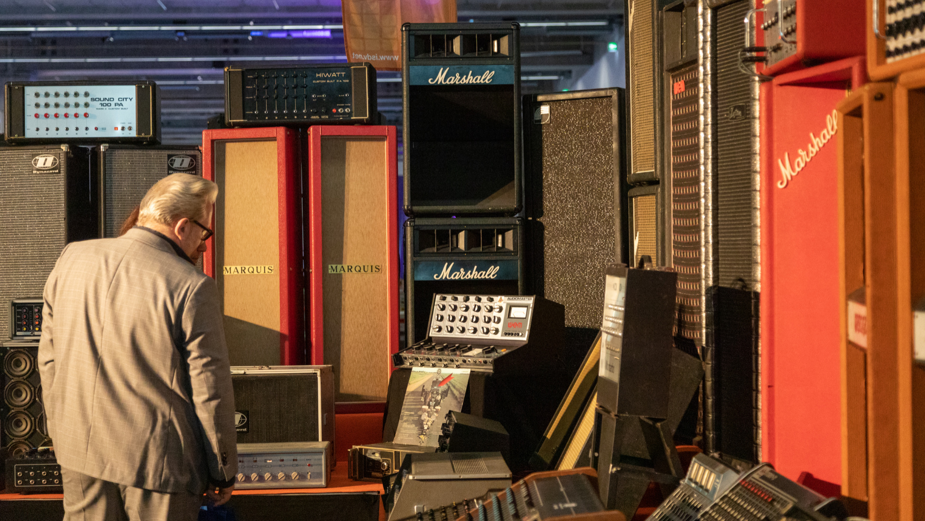 A man stands in front of old concert sound systems